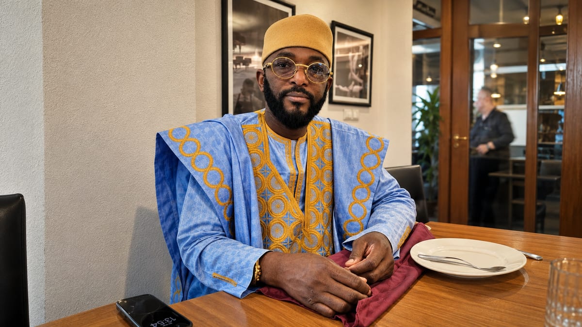 Marabout Djibril de túnica azul e dourada, sentado em consulta